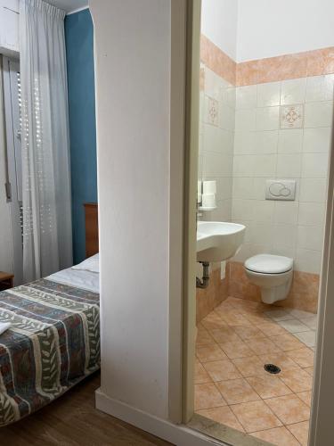 uma casa de banho com uma cama, um lavatório e um WC. em Hotel Stella D'Italia em Rimini