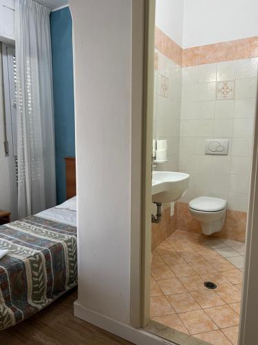 a bathroom with a bed and a sink and a toilet at Hotel Stella D'Italia in Rimini