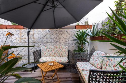 a patio with two chairs and a table and an umbrella at 1 Bedroom Apartment with cosy Backyard close to Valletta in Il-Furjana
