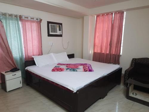 a bedroom with a large bed with red curtains at Hotel Geetanjali Palace in Kalyani