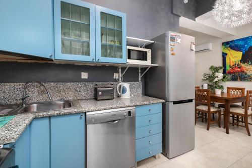a kitchen with blue cabinets and a stainless steel refrigerator at 1 Bedroom Apartment with cosy Backyard close to Valletta in Il-Furjana