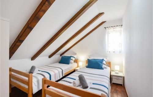 two beds in a room with white walls and wooden beams at Gorgeous Home In Trilj With House A Mountain View in Trilj