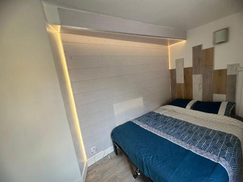 1 dormitorio con 1 cama con pared de madera en suite spa jacuzzi tout confort, en Beaumont-sur-Oise
