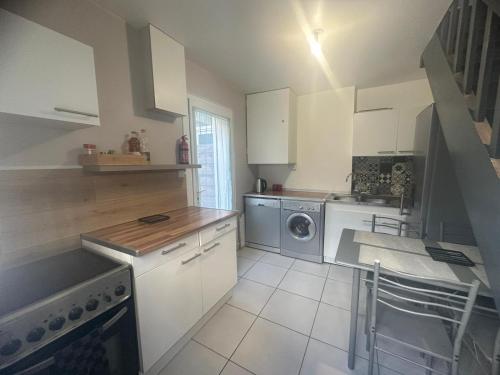 cocina con armarios blancos, lavadora y secadora en suite spa jacuzzi tout confort, en Beaumont-sur-Oise