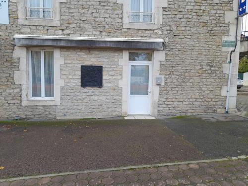 - un bâtiment en briques avec une porte blanche devant dans l'établissement Appartement Au Bord Du Canal, à Montbard