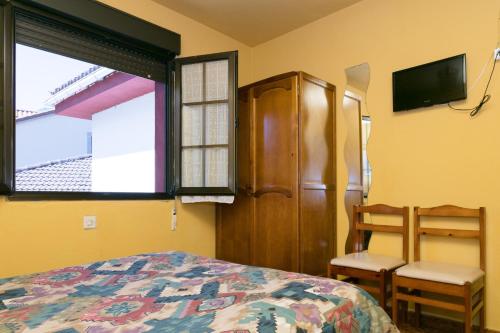 1 dormitorio con 1 cama, 2 sillas y TV en Pensión Casa Cesáreo, en Pola de Somiedo