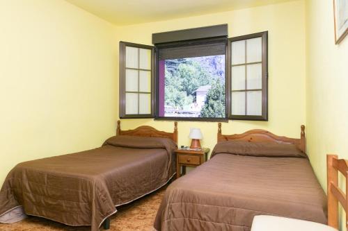 two beds in a room with two windows at Pensión Casa Cesáreo in Pola de Somiedo