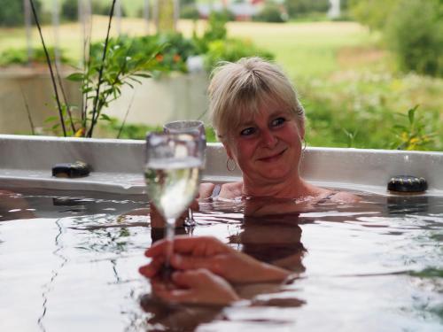 a woman in a bathtub with a glass of water at Lensmannsgården in Namdalseid