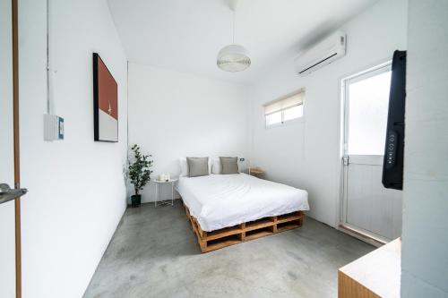 a white bedroom with a bed and a window at Ling Inn in Kaohsiung