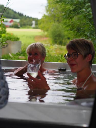 two women in a bathtub with a glass of wine at Lensmannsgården in Namdalseid