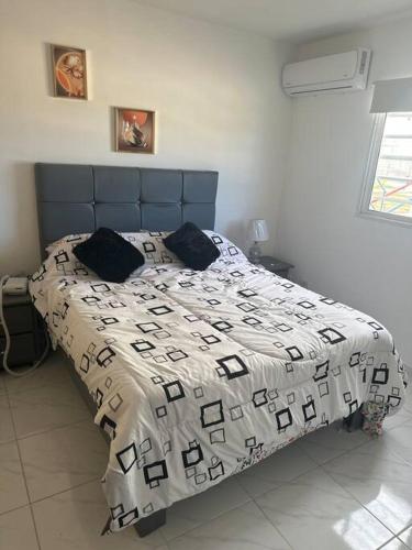 Cumayasa Kilómetros 4 1/2にあるCozy apartment Terrazas del Este La Romanaのベッドルーム1室(白と黒の掛け布団付きのベッド1台付)