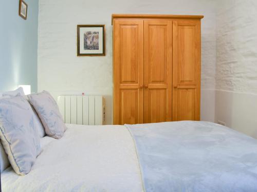 a bedroom with a bed and a wooden cabinet at Trenay Barns Cottage in Warleggan