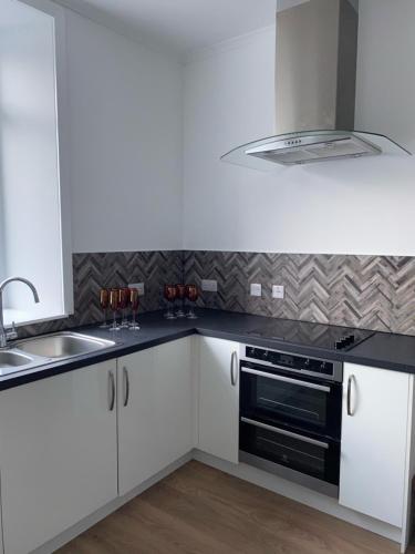 a kitchen with white cabinets and a sink and a stove at ARDUTHIE STREET in Stonehaven