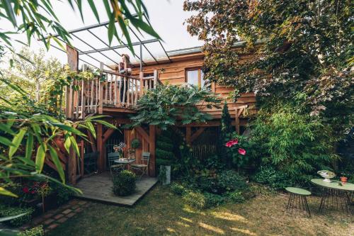 a garden with a wooden house with a balcony at La cabane du bon chemin ,spa in Laval