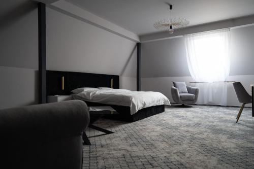 a bedroom with a bed and a chair and a window at Hotel Cristal in Cluj-Napoca