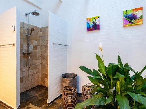 La salle de bains est pourvue d'une douche et d'une plante en pot. dans l'établissement Holiday home Ålbæk LXXXVI, à Ålbæk