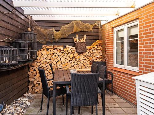 eine Terrasse mit einem Tisch, Stühlen und einem Stapel Holz in der Unterkunft 6 person holiday home in Lemvig in Lemvig