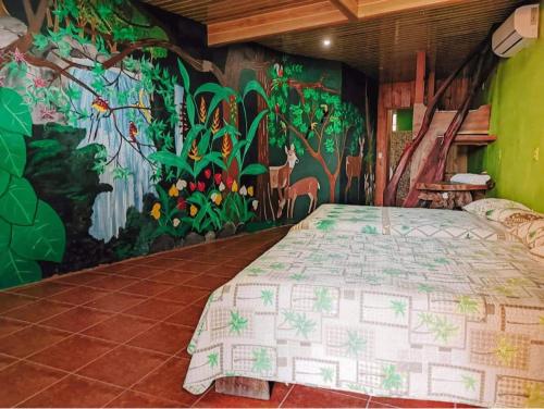 Schlafzimmer mit einem Bett mit Wandgemälde in der Unterkunft La Perla Negra Eco Pirate Resort in Puntarenas