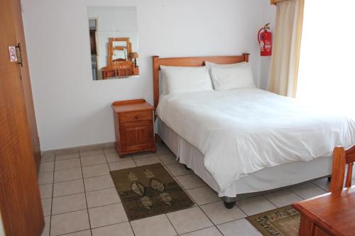 een slaapkamer met een bed, een tafel en een spiegel bij El Palmar Guesthouse in Groblersdal