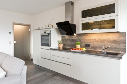 a kitchen with white cabinets and a sink at Kells Appartements in Klink