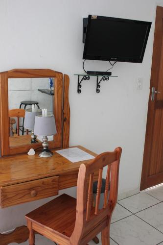 einen Schreibtisch mit einem Spiegel und einen TV an der Wand in der Unterkunft El Palmar Guesthouse in Groblersdal