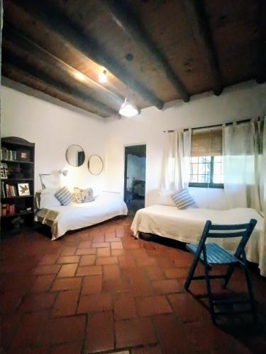 a bedroom with two beds and a chair in it at Casa Darragueira de Chacras de Coria in Chacras de Coria