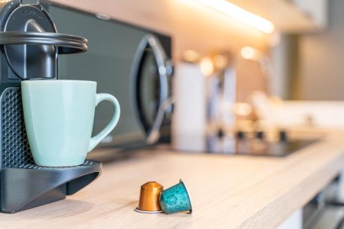 une tasse de café assise sur un comptoir à côté d'un évier dans l'établissement **Le Classique** - Appartement 40m² à 500m de la Place d'Armes de Douai, à Douai