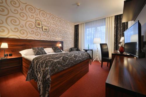 a hotel room with a bed and a flat screen tv at Parkhotel Morris Novy Bor in Nový Bor