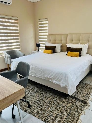 a bedroom with a large white bed and a chair at Ultimate Sky-3 bedroom villa in Pretoria