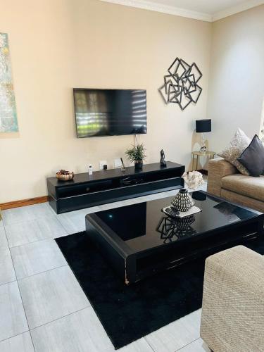 a living room with a couch and a tv at Ultimate Sky-3 bedroom villa in Pretoria