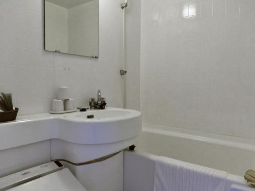 a white bathroom with a sink and a bath tub at Gardenvilla Shirahama in Shimoda