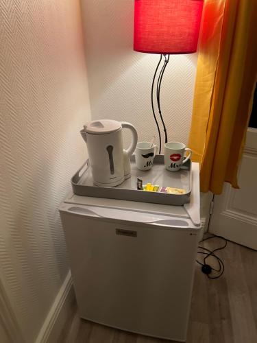 - une table avec deux tasses et une lampe au-dessus du réfrigérateur dans l'établissement Chambre sur la falaise de Pontaillac, à Vaux-sur-Mer