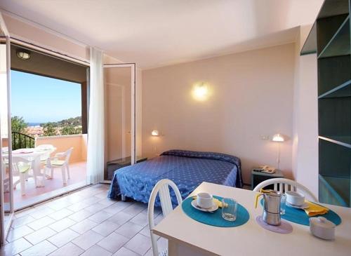 a bedroom with a bed and a table and a balcony at Hotel Residence isola verde in Marciana Marina