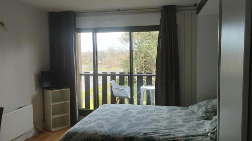 um quarto com uma cama e uma varanda com uma janela em Studio tout confort au bord du lac d'Estey em Dax