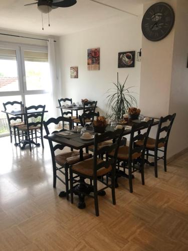 a dining room with a table and chairs and a clock at Hôtel Le Relais in Fleurance