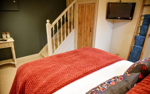 a bed with a red blanket in a room at The Folly in Sedbergh