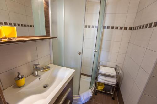 y baño con lavabo y ducha. en Azúr Ház Kamilla Apartman, en Sárvár