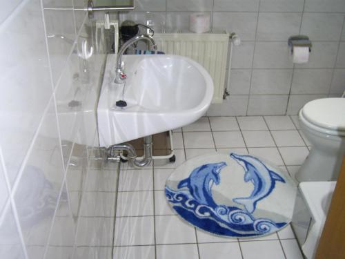 uma casa de banho com um lavatório e um WC com um tapete de ondas azuis em Wohnung in Wilhelmsfehn mit Terrasse, Garten und Grill em Wiesmoor