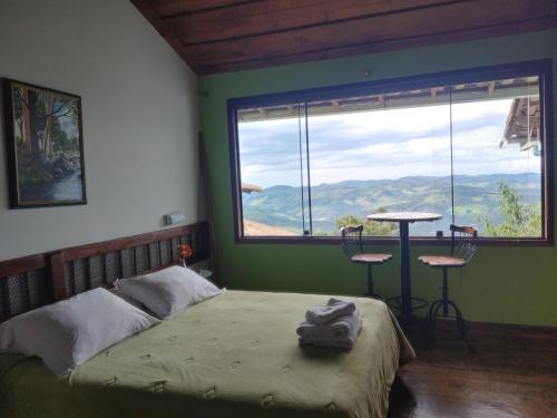 a bedroom with a bed and a large window at Chales Quinteto de Cores in Lavras Novas