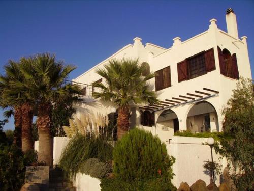 a white house with palm trees in front of it at Kis-Kis in Metókhion Ayías Kiriakís