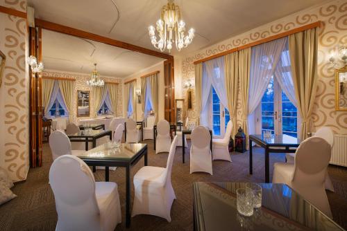 a restaurant with white chairs and tables and windows at Parkhotel Morris Novy Bor in Nový Bor