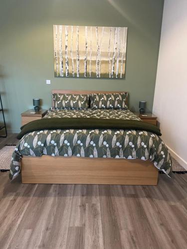 a bedroom with a large bed with a wooden floor at Modern Barn Conversion in Brackley