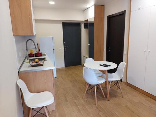 Bakuriani Inn Apartment 13 في باكورياني: مطبخ مع طاولة وكراسي بيضاء في الغرفة
