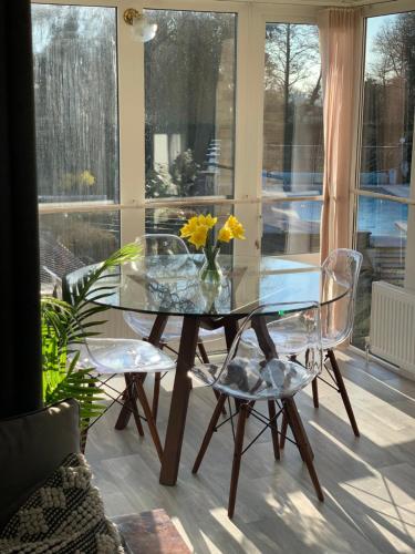 een glazen tafel met 2 stoelen en een vaas met bloemen bij Lovely two bedroom Annexe close to Newbury 