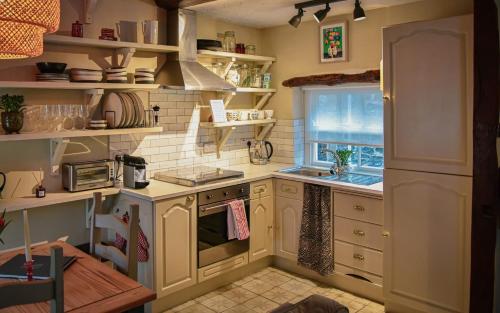 a kitchen with white cabinets and a stove and a window at The Folly in Sedbergh