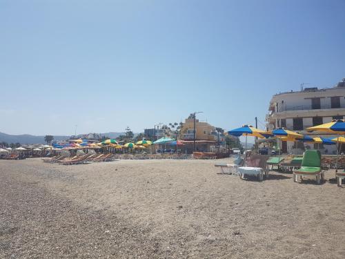 a beach with many chairs and umbrellas and tables at Bright & Comfy Apartments near the beach in Kos Town