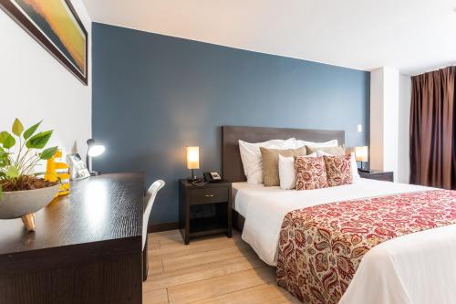 a hotel room with a large bed and a desk at Hotel Carretero in Manizales