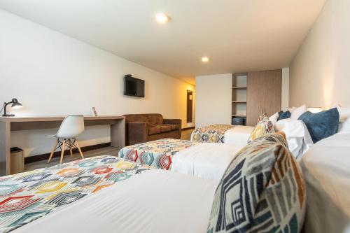 a hotel room with three beds and a couch at Hotel Carretero in Manizales