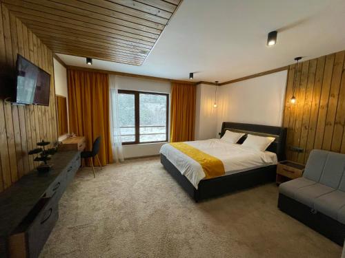 ein Schlafzimmer mit einem Bett, einem Sofa und einem TV in der Unterkunft 4U LUXURY VILLA in Dospat