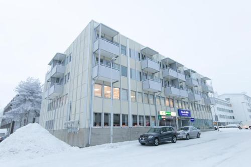 un edificio cubierto de nieve con coches aparcados delante de él en Hilma's apartment, en Rovaniemi
